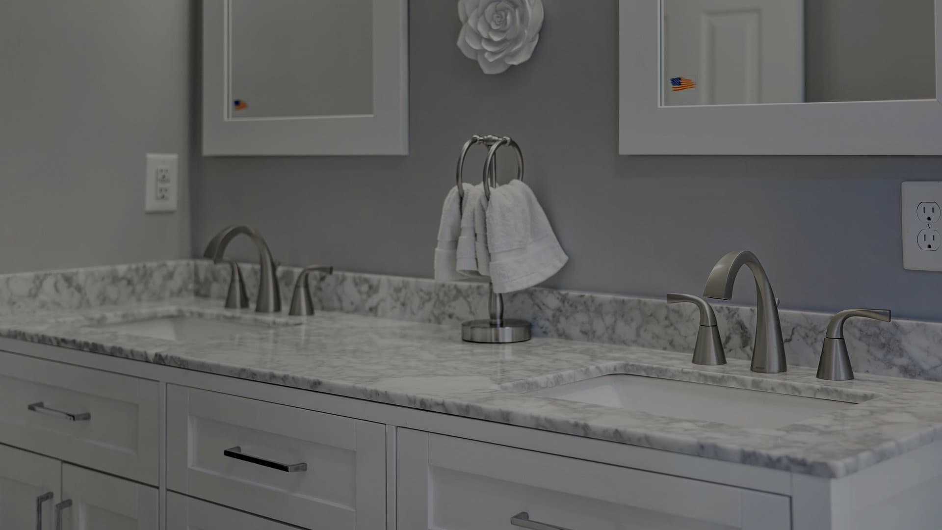 Double vanity bathroom with marble countertop, white shaker cabinets, and brushed nickel fixtures